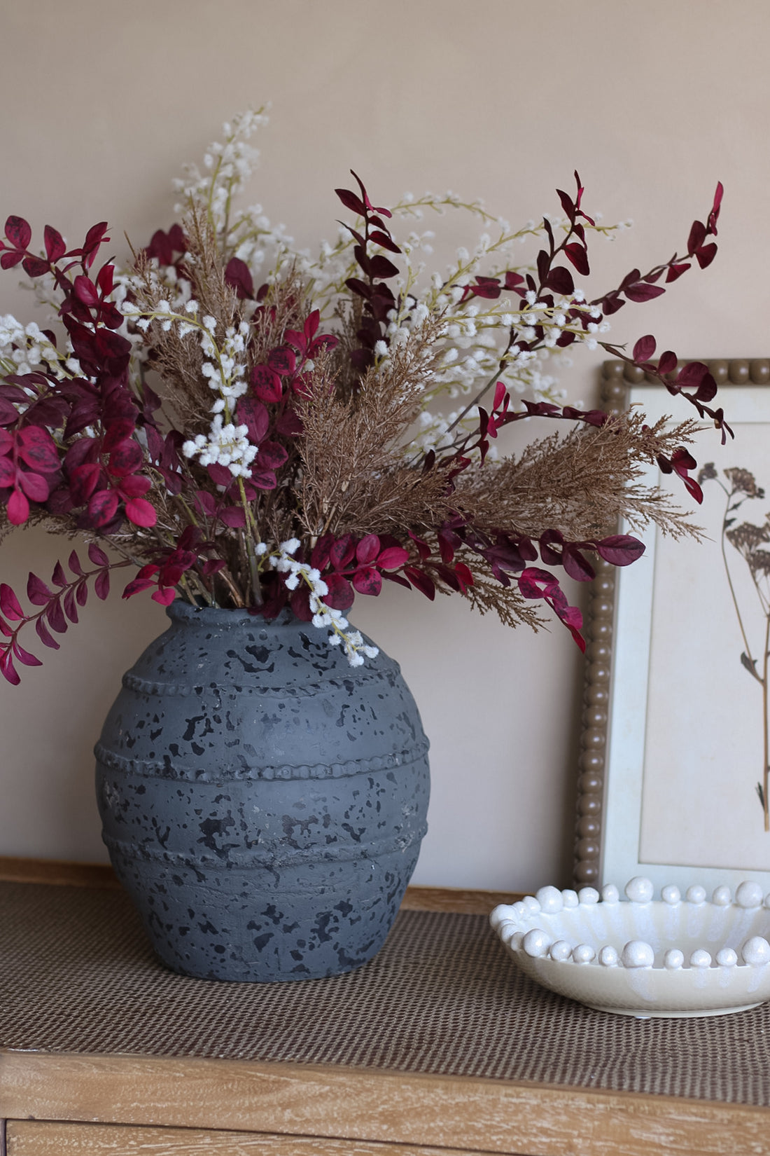 Faux autumn luxury foliage arrangement in charcoal ribbed vase with white bobble bowl and vintage brown framed wall art