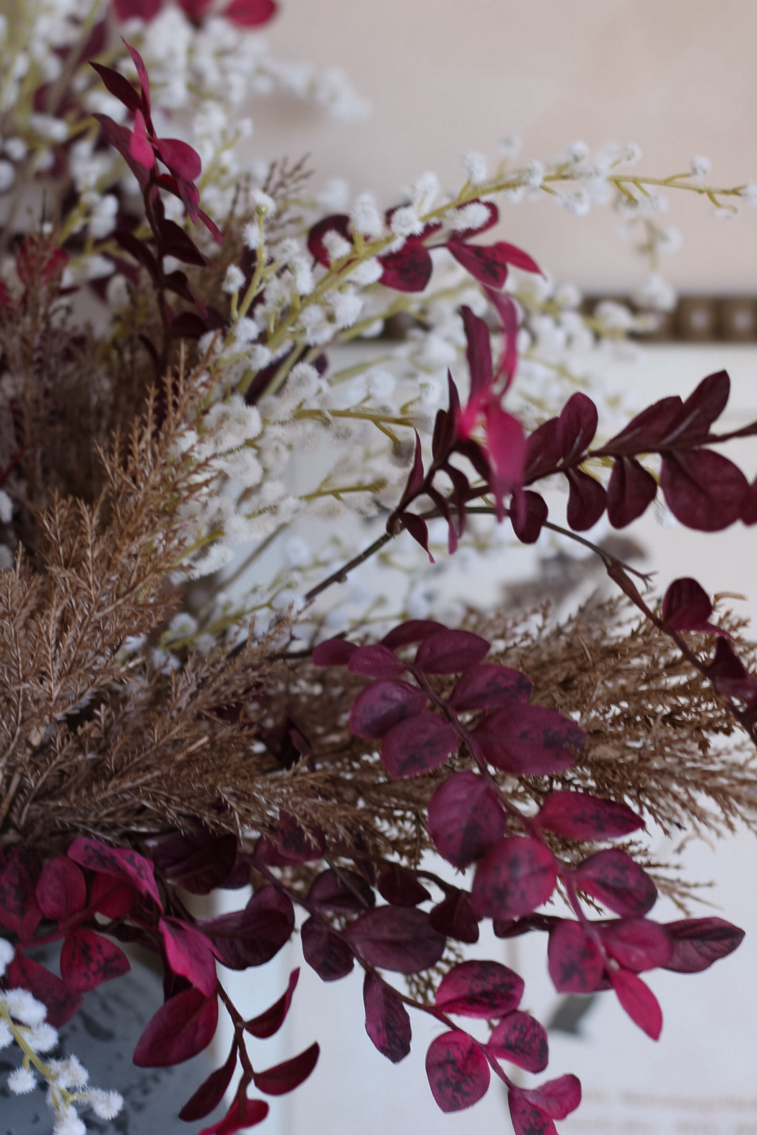 Close-up of a Autumn foliage bouquet with brown, plum and white flowers on a neutral background