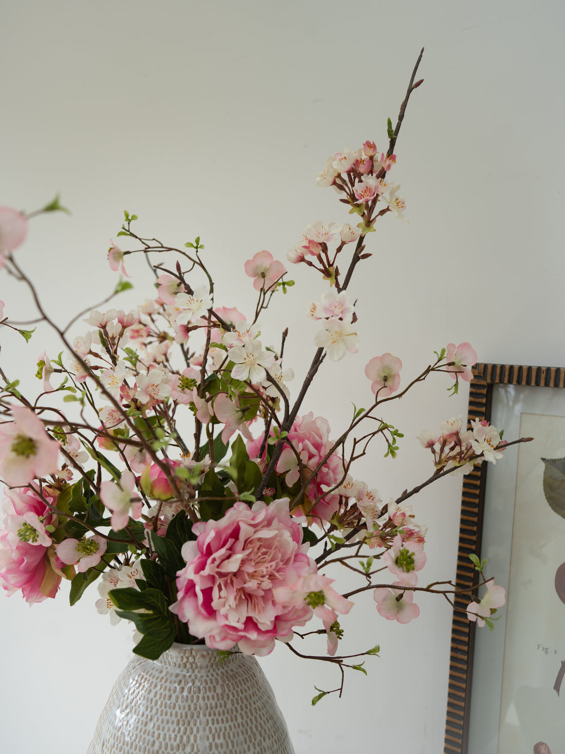 Vase with pink flowers against a white wall