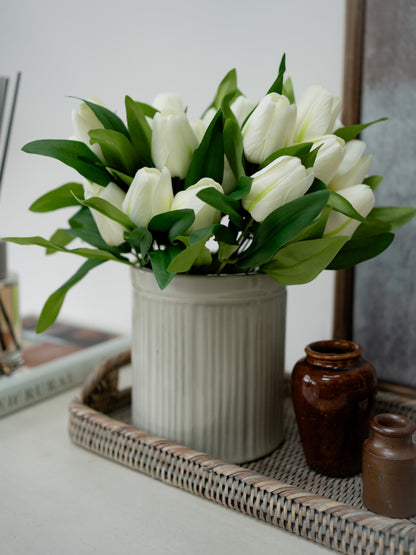 White tulips in a vase on a decorative tray with a blurred background