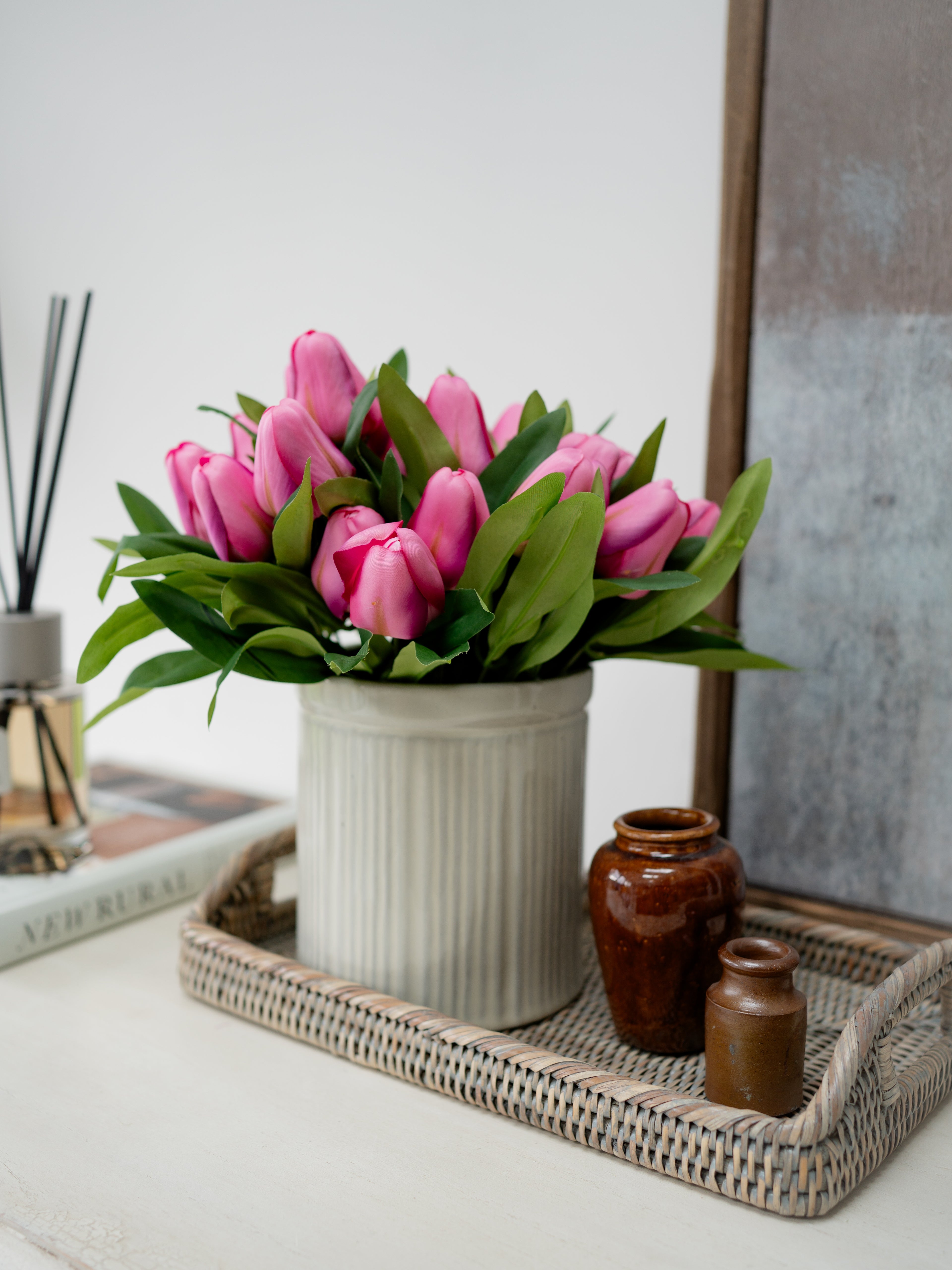 faux Pink tulips in a white vase on a decorative tray with a neutral background