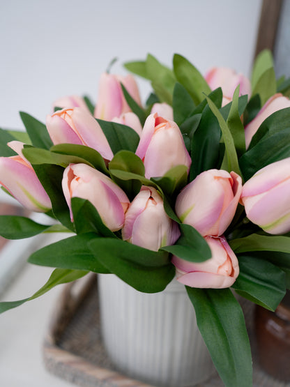 Bouquet of faux pink tulips in a white vase on a light background