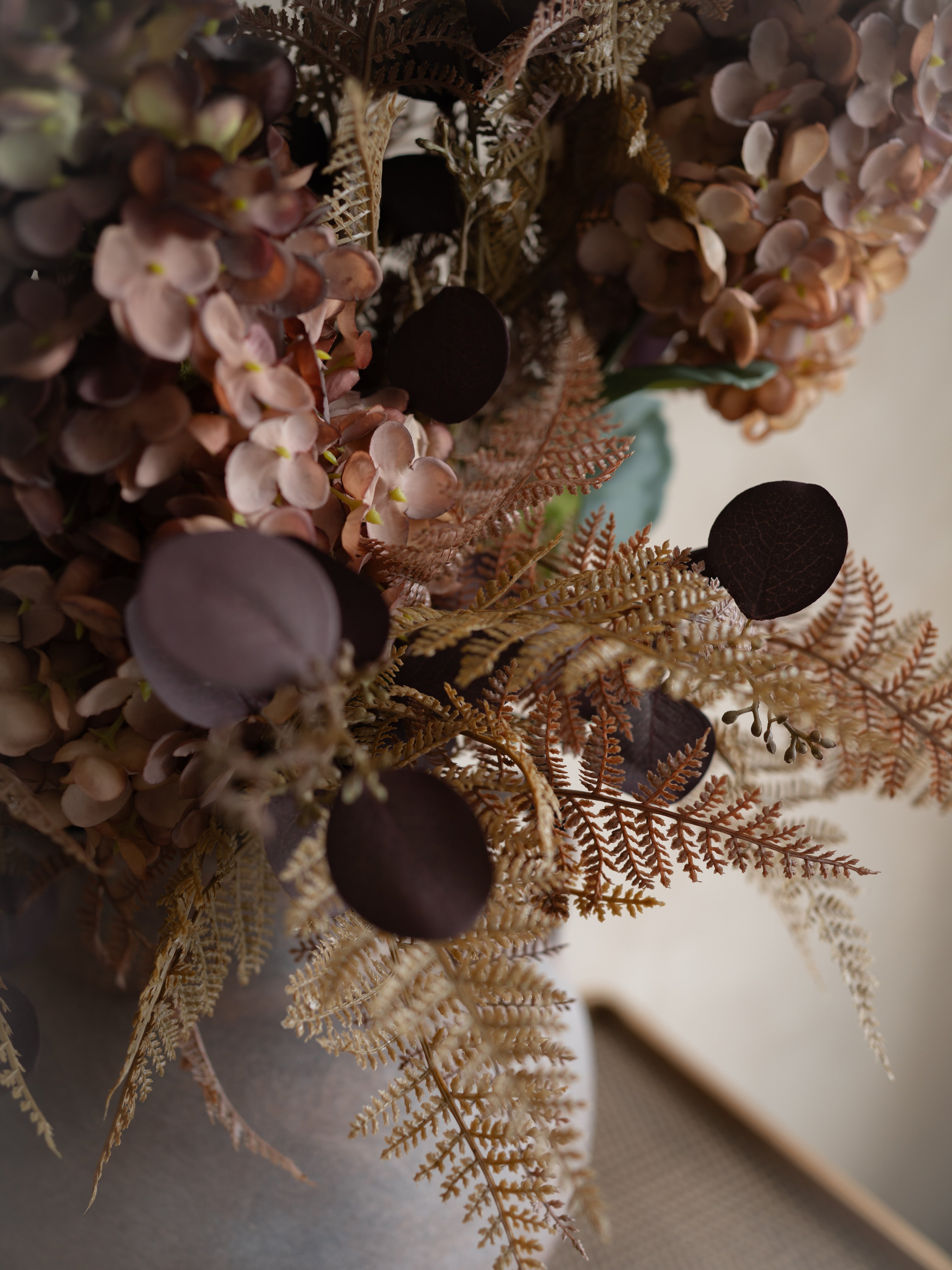 Close-up of a floral arrangement with autumn flowers and leaves on a neutral background