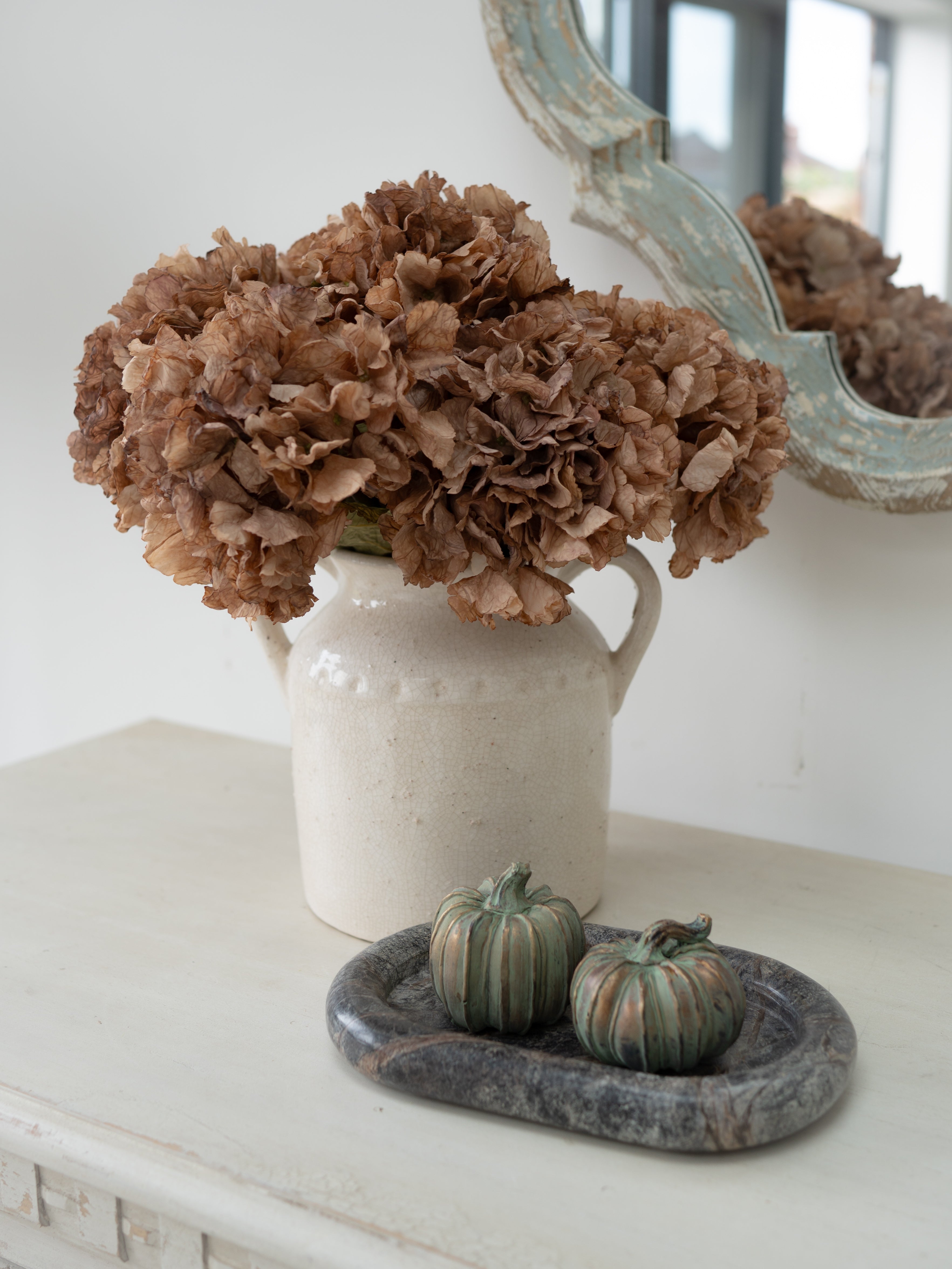 Faux Cappuccino Dried Ruffle Hydrangea in rustic white dual handled vase with autumn inspired pumpkins on green marble keepall tray