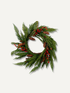 A natural pine and cedar holiday wreath decorated with green needles, brown pinecones, and clusters of small red berries, shown on a light gray background.