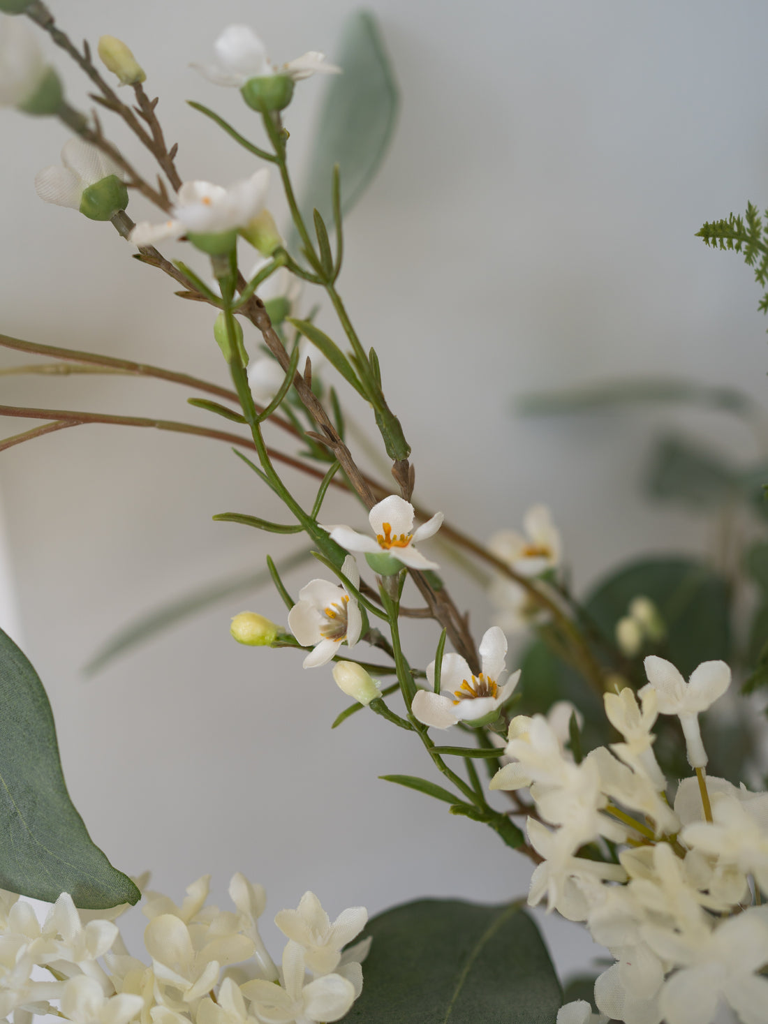 Close-up of faux white flowers with green leaves on a blurred background