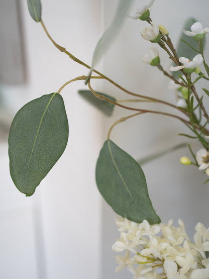 Close-up of faux green leaves and white flowers on a blurred background