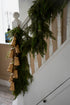 Decorative faux green cypress garland with gold bells on a staircase