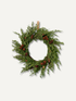 A faux christmas green evergreen wreath decorated with small brown pinecones and a natural wood hanging loop, shown against a plain light gray background.