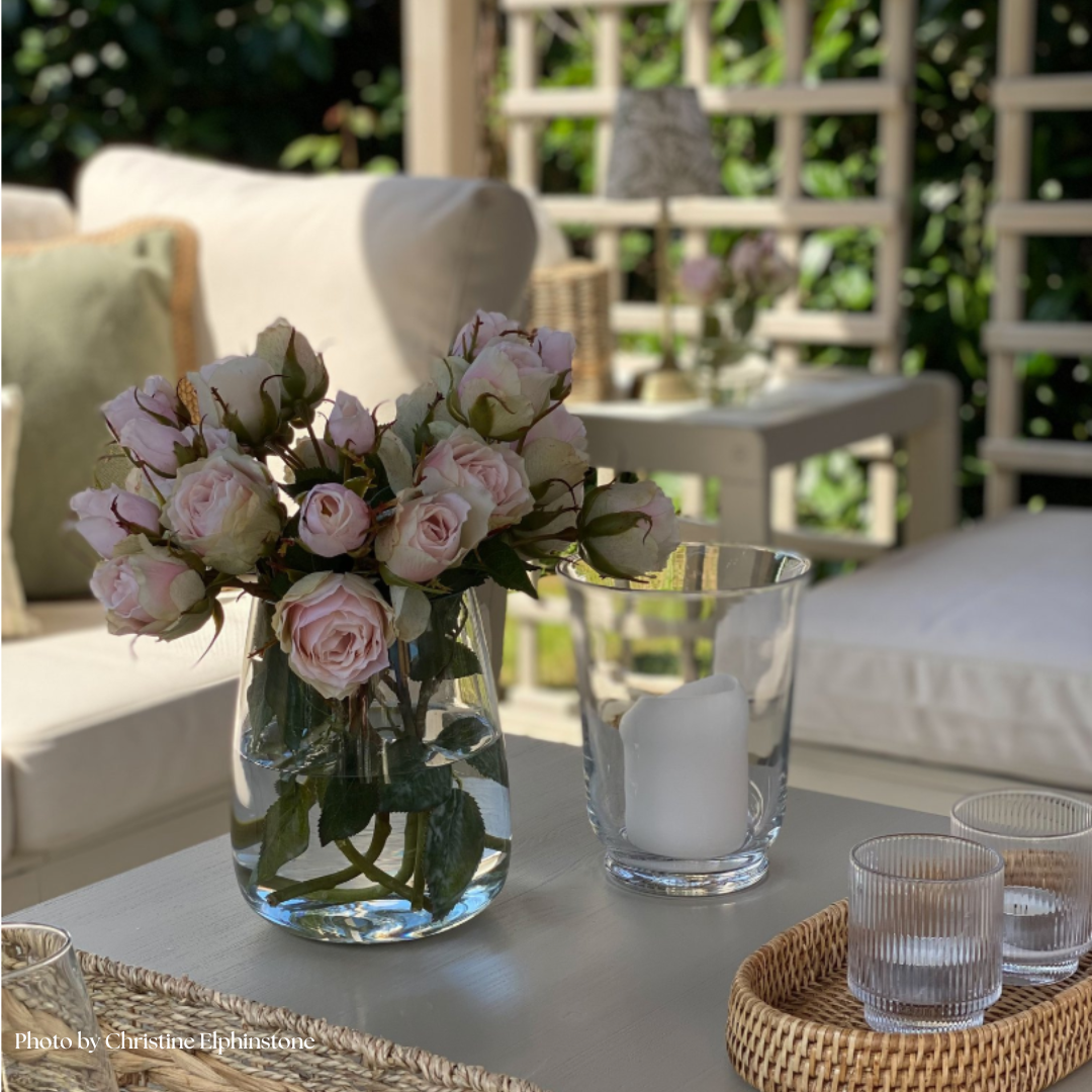 Realistic faux soft pink roses in glass vase for home decor