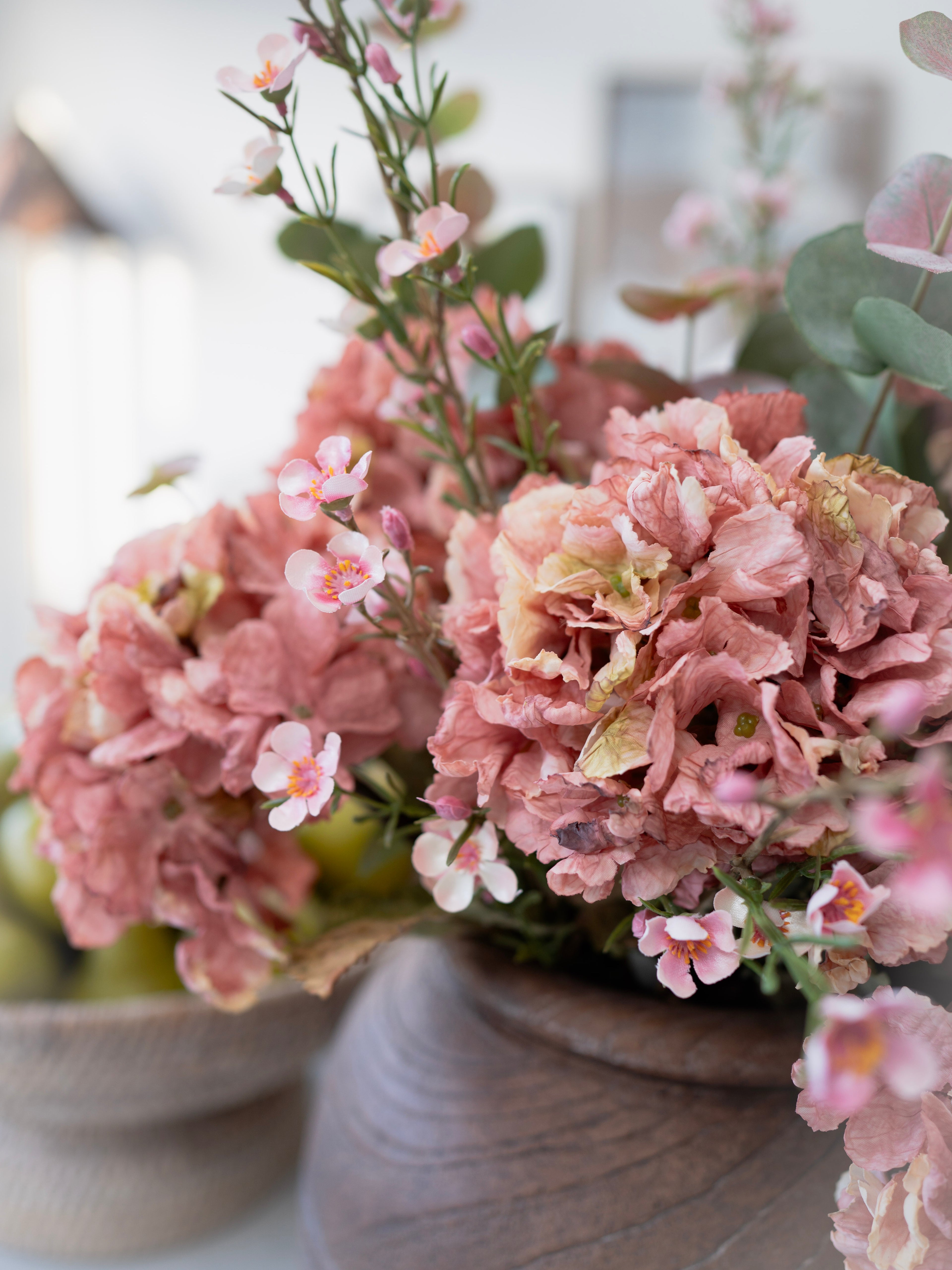 faux pink flowers in a vase with a blurred background