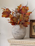 Decorative vase with autumn-themed leaves on a white surface