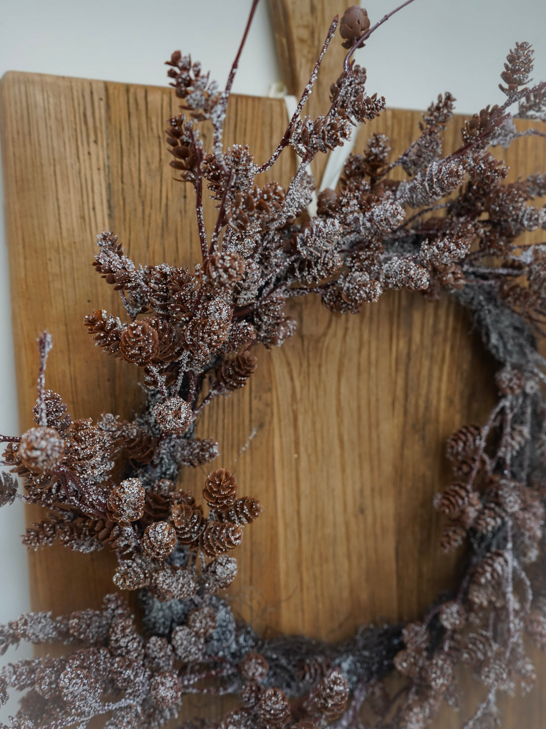 Decorative wreath with pinecones and branches on a wooden board