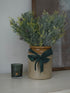Decorative vase with Faux Glitter Pine Spray with Cones and a candle on a surface