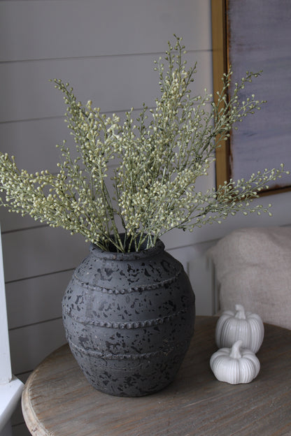Decorative vase with faux autumn branches on a wooden table against a neutral wall.