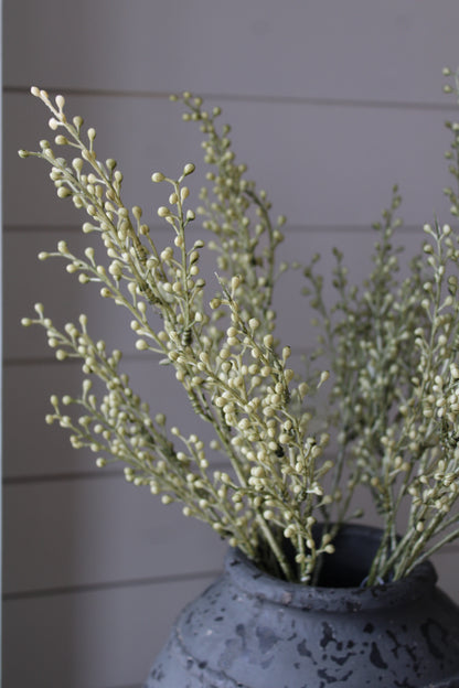 Vase with autumn foliage and greenery against a gray wall