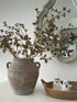 vintage style olive pot filled with faux huckleberry stems with rattan tray with decorative autumn ghost ornaments in the foreground