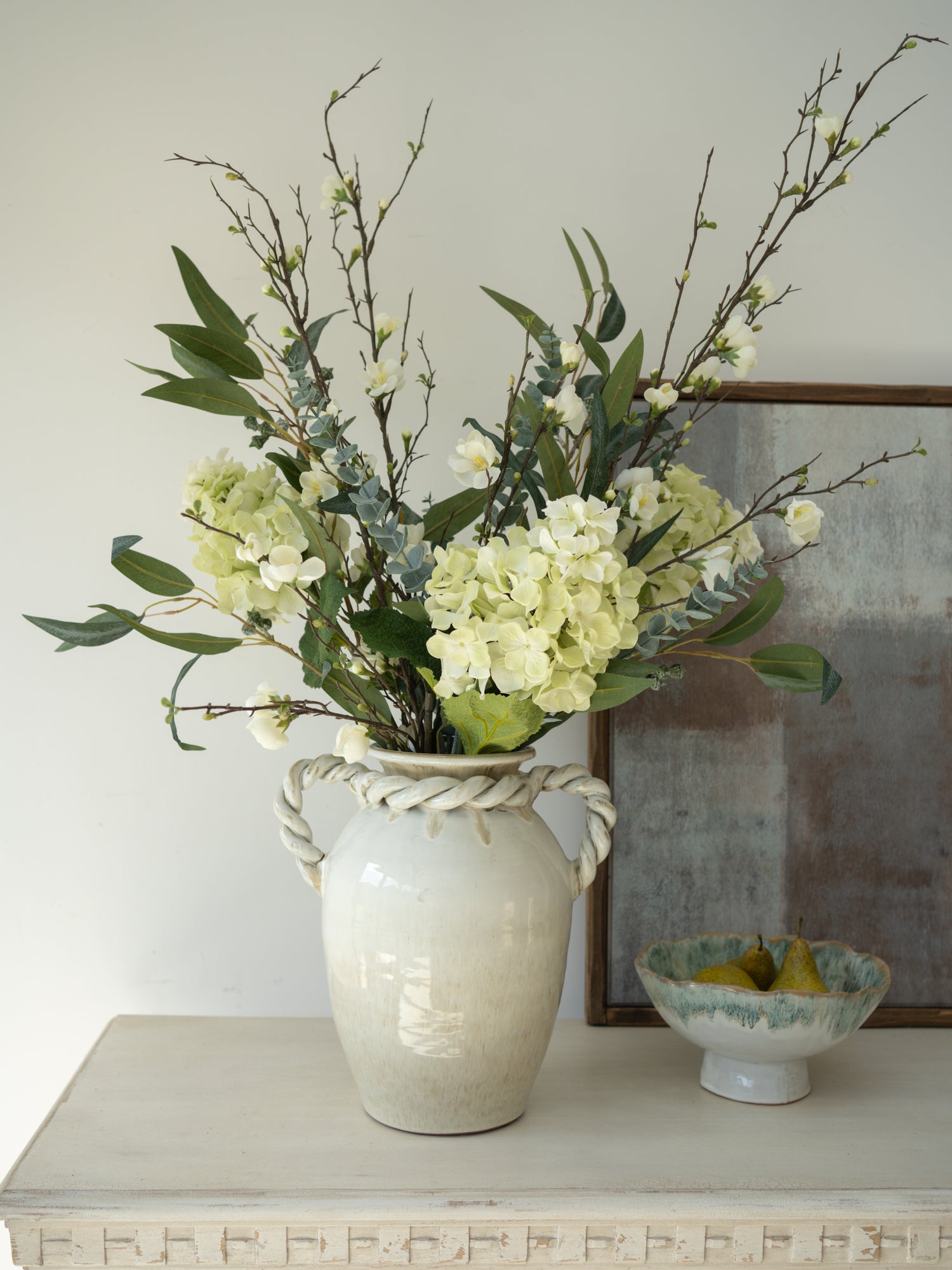 Floral arrangement in a textured vase on a table with a neutral background