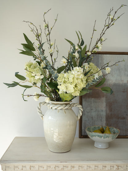 Floral arrangement in a textured vase on a table with a neutral background