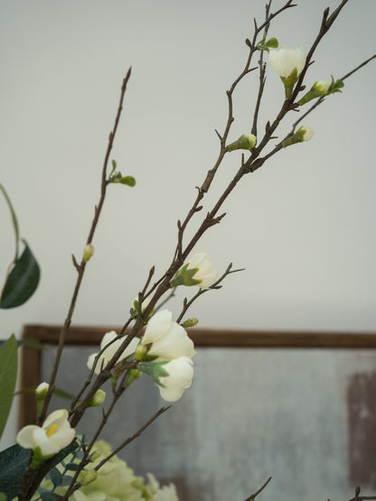 Branches with  faux white flowers against a neutral background