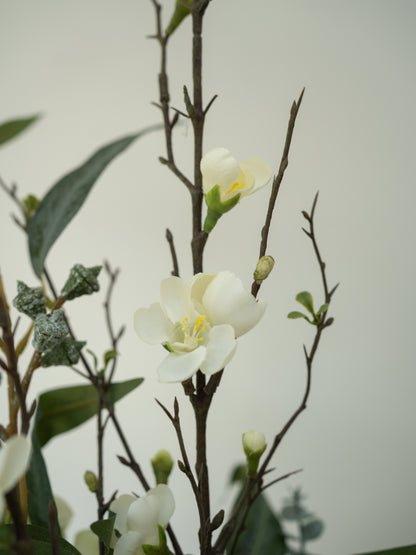 Faux white flowers and green leaves on a blurred background