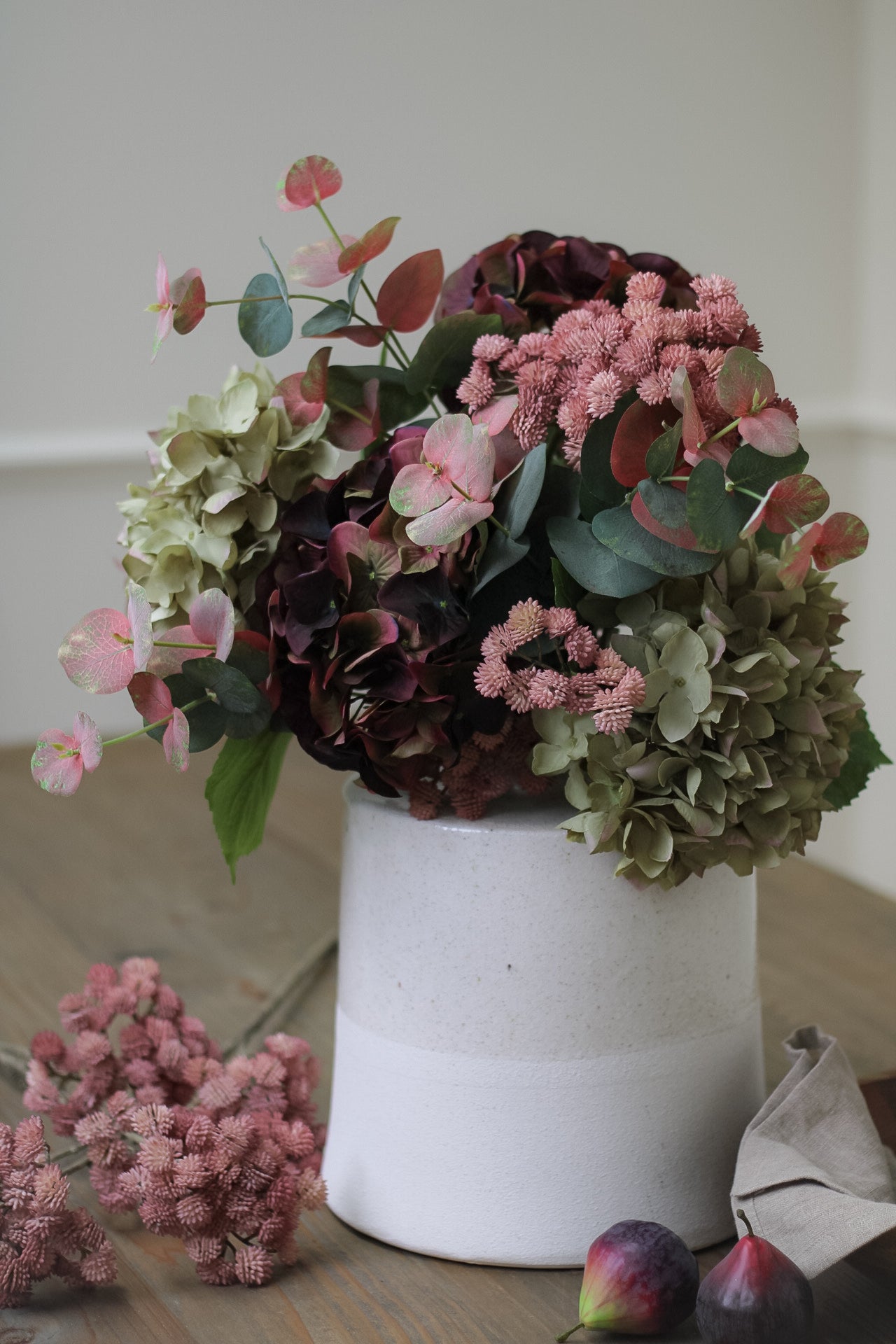 faux burgundy and soft green autumn hydrangea floral arrangement in distressed white vase