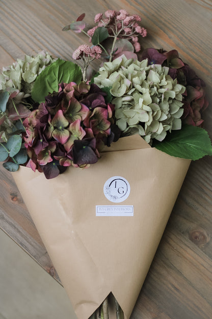 faux autumn floral arrangement wrapped in brown paper