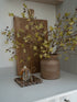 Decorative faux oak and acorns branch arrangement with a vase, branches, and small vase on a shelf.