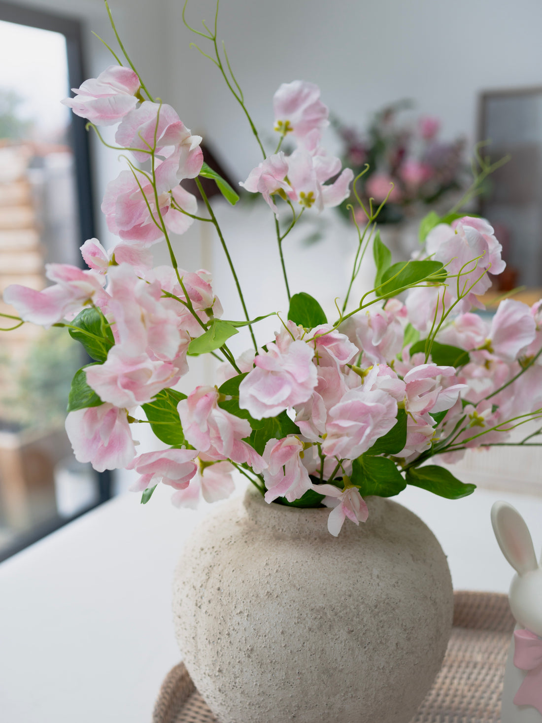 Pink flowers in a stone vase on a table with a blurred background