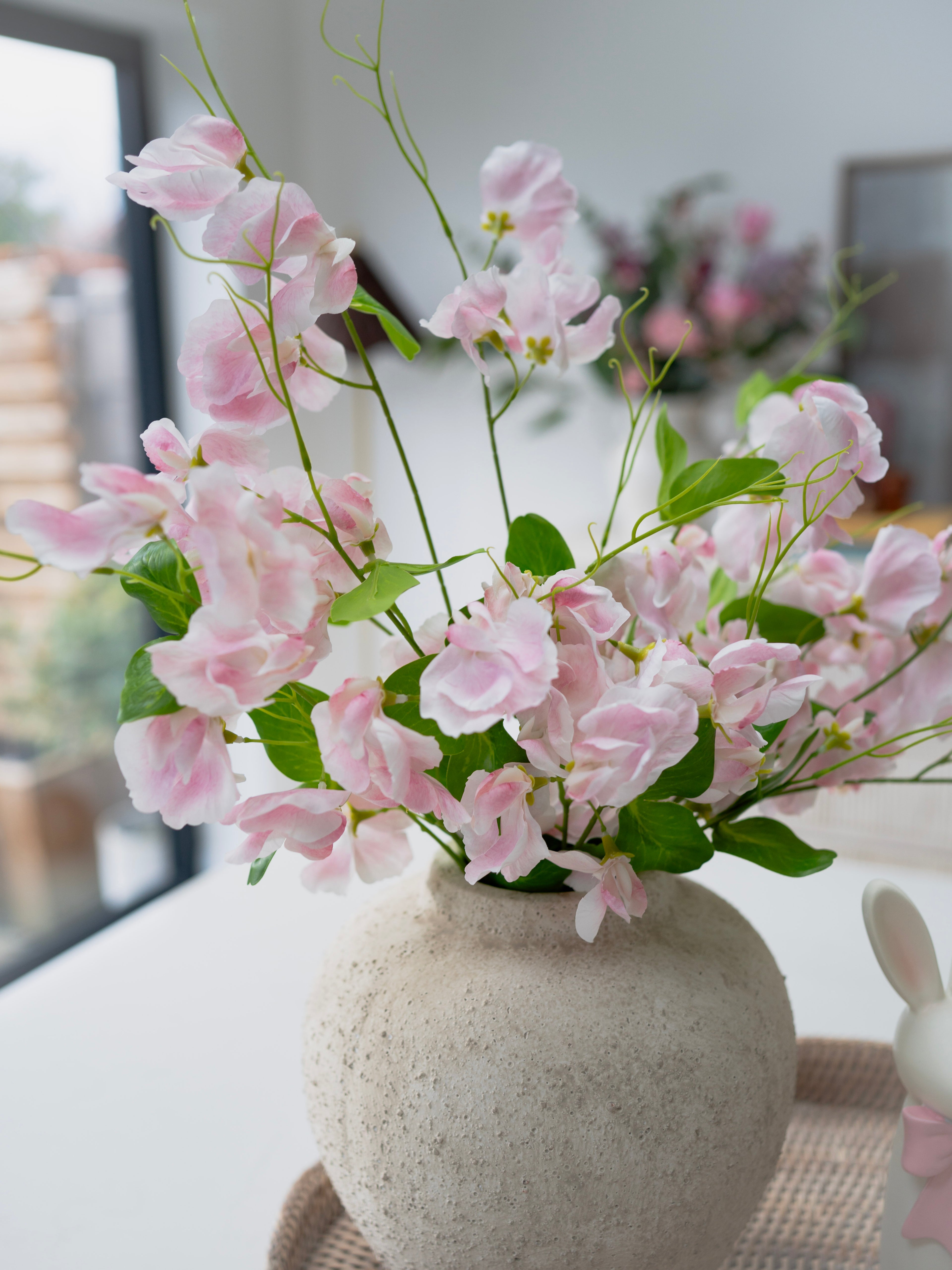Pink flowers in a stone vase on a table with a blurred background