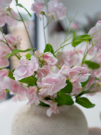 Pink flowers in a white vase on a blurred background