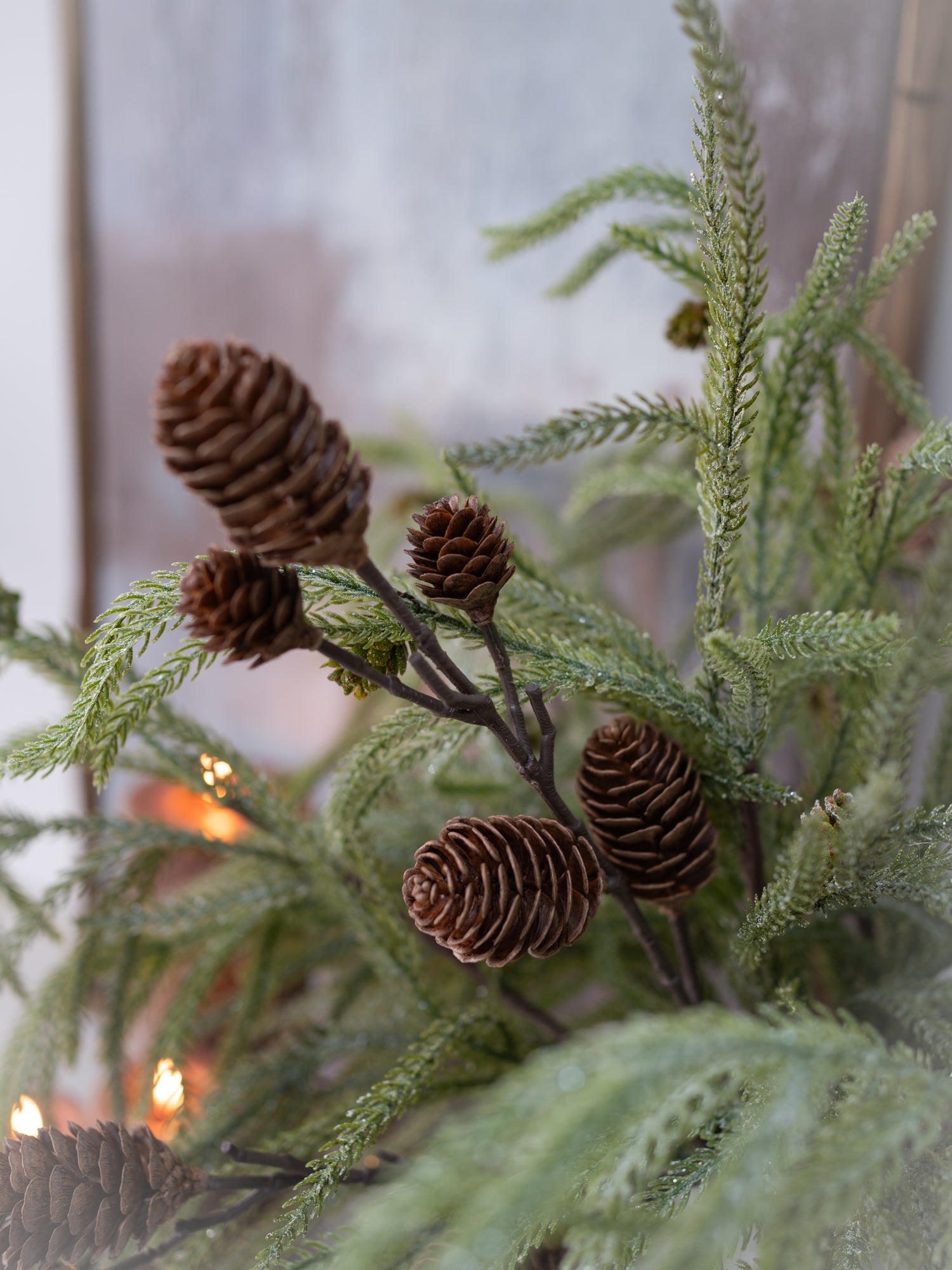 Decorative arrangement with greenery and pine cones in a softly blurred indoor setting