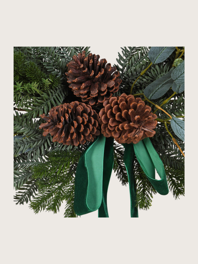 Decorative arrangement with pine cones and green ribbons on a white background