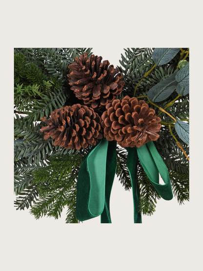 Decorative arrangement with pine cones and green ribbons on a white background