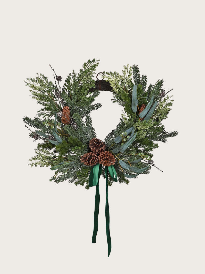 Christmas wreath with greenery, pinecones, and ribbons on a light gray background