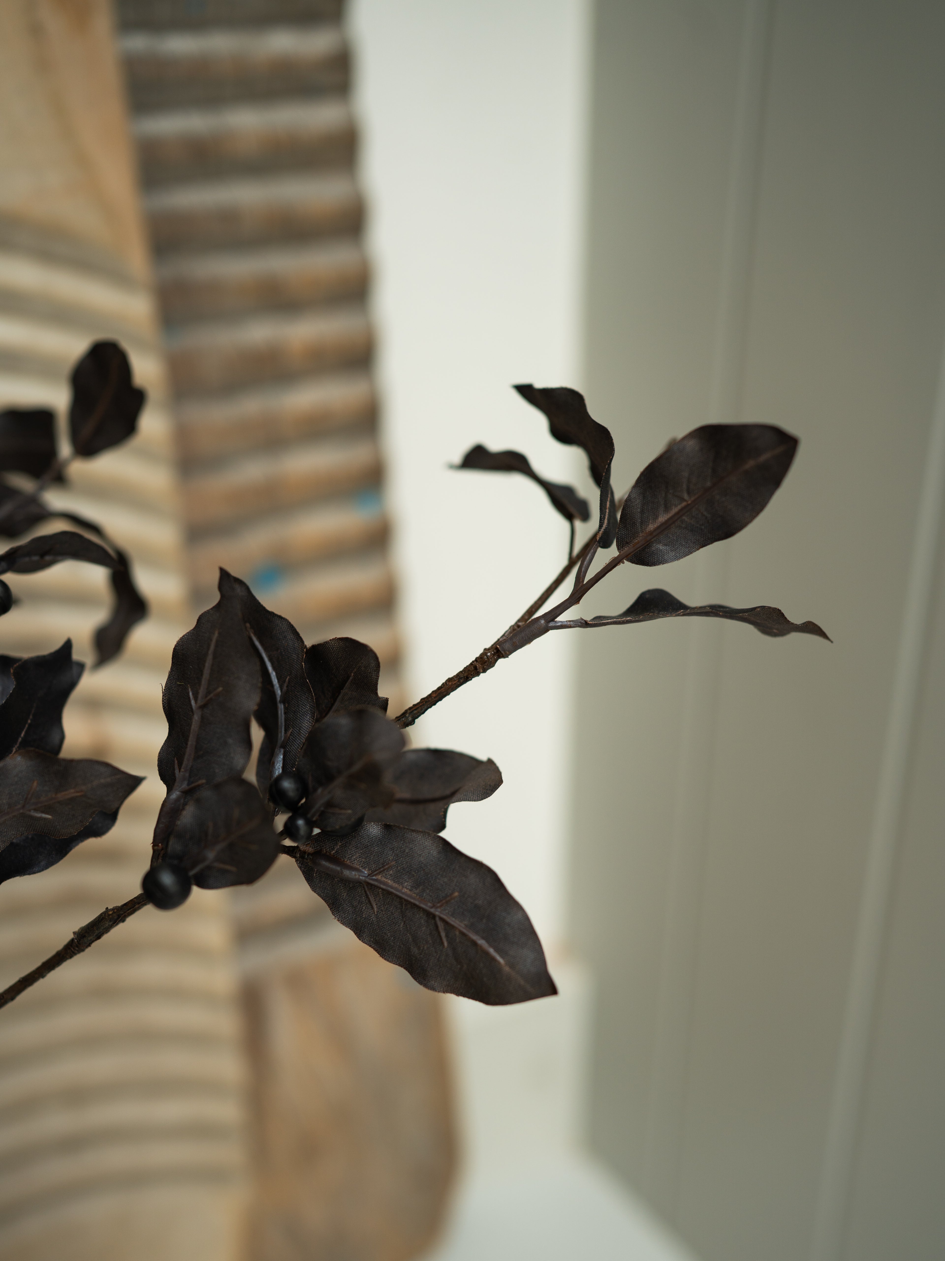 Artificial Faux Pittosporum Tom Thumb Spray leaves on a branch against a neutral background