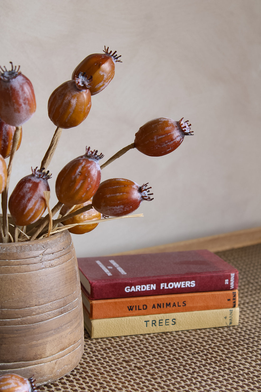 Dried flowers in a vase with books titled &