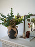 Faux Purple Hydrangea, Hops and Eucalyptus Floral Arrangement in black cement ridged vase with hessian bow