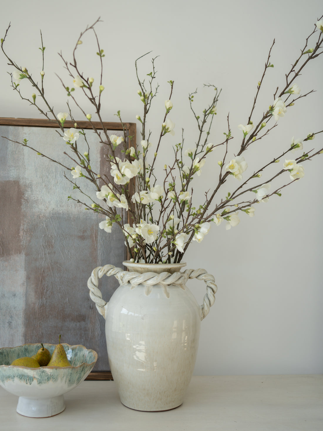 White vase with branches and blossom flowers on a neutral background