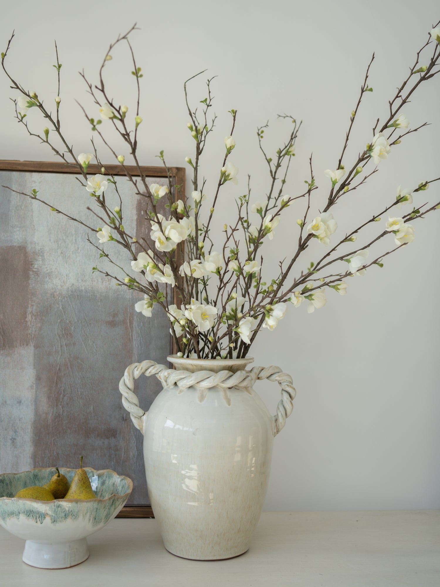 White vase with branches and blossom flowers on a neutral background