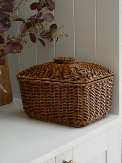 Wicker bread box on a white surface with a neutral background