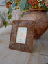 Wicker picture frame with a floral arrangement in the background