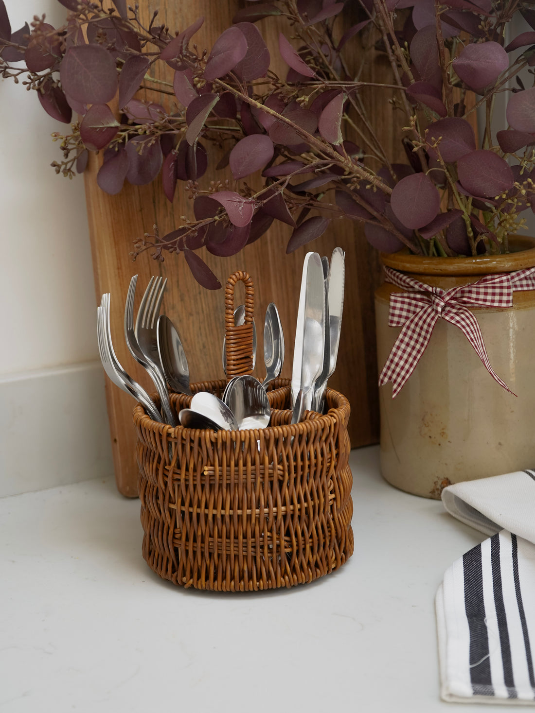 Wicker basket with cutlery on a countertop with decorative elements