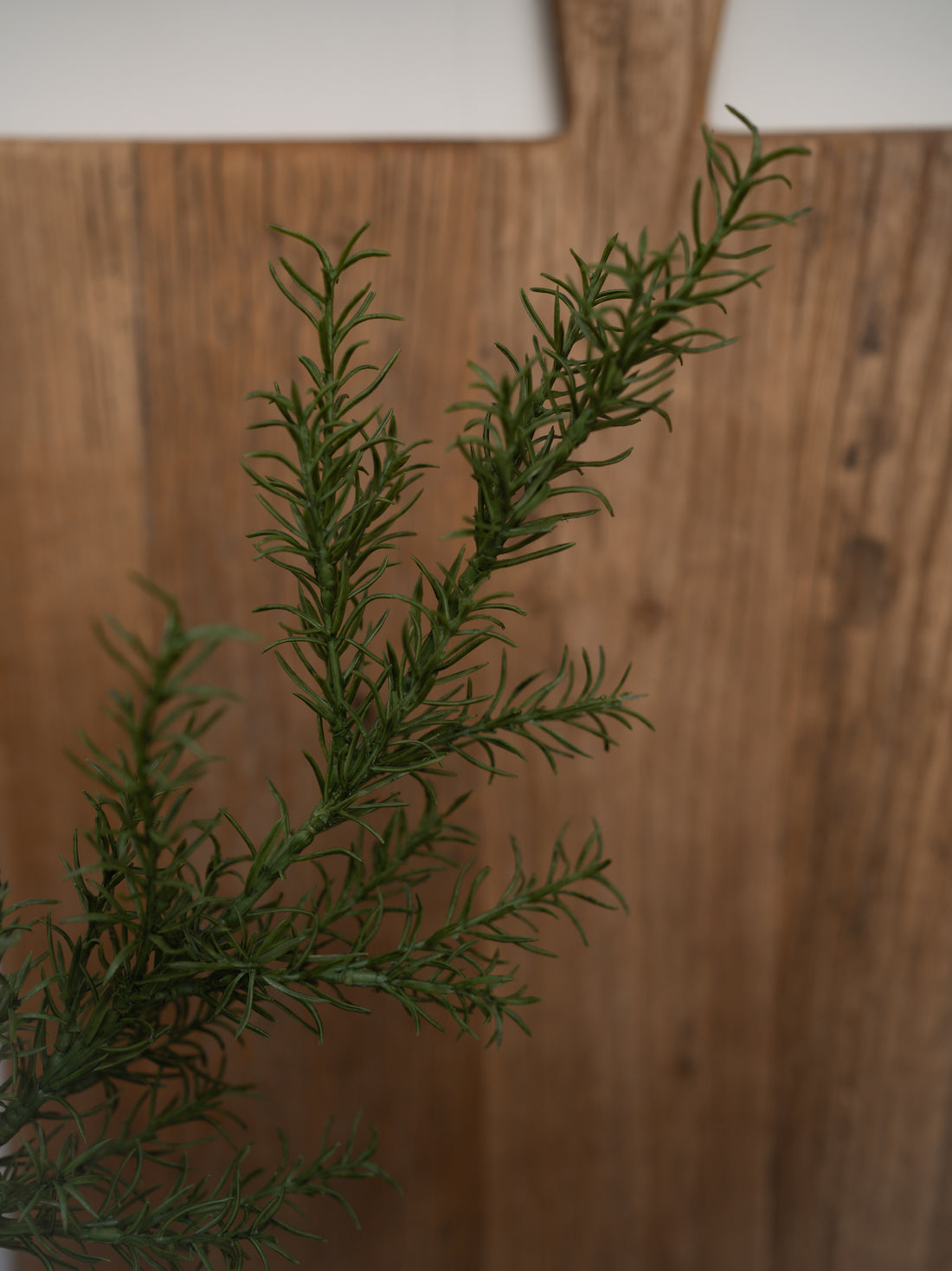 faux rosemary branch against a wooden background