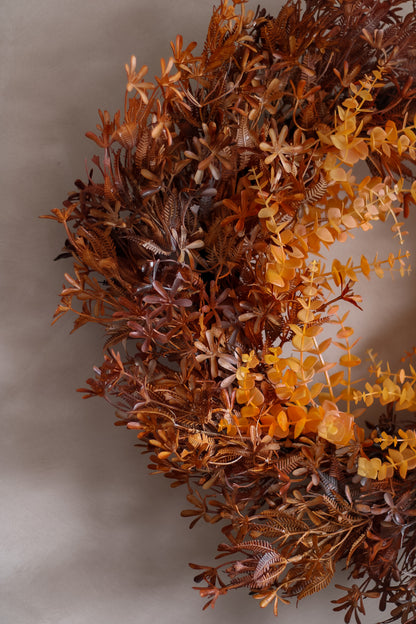 Wreath made of dried leaves and flowers on a neutral background