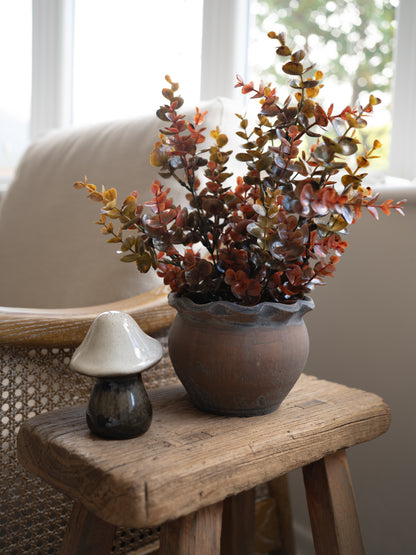 Faux Rustic Autumn Eucalyptus Plant in scalloped rustic plant pot with small stoneware mushroom on wooden table