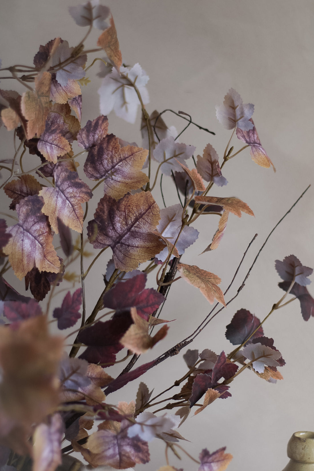 Artificial leaves with brown, purple, and orange hues on a plain background