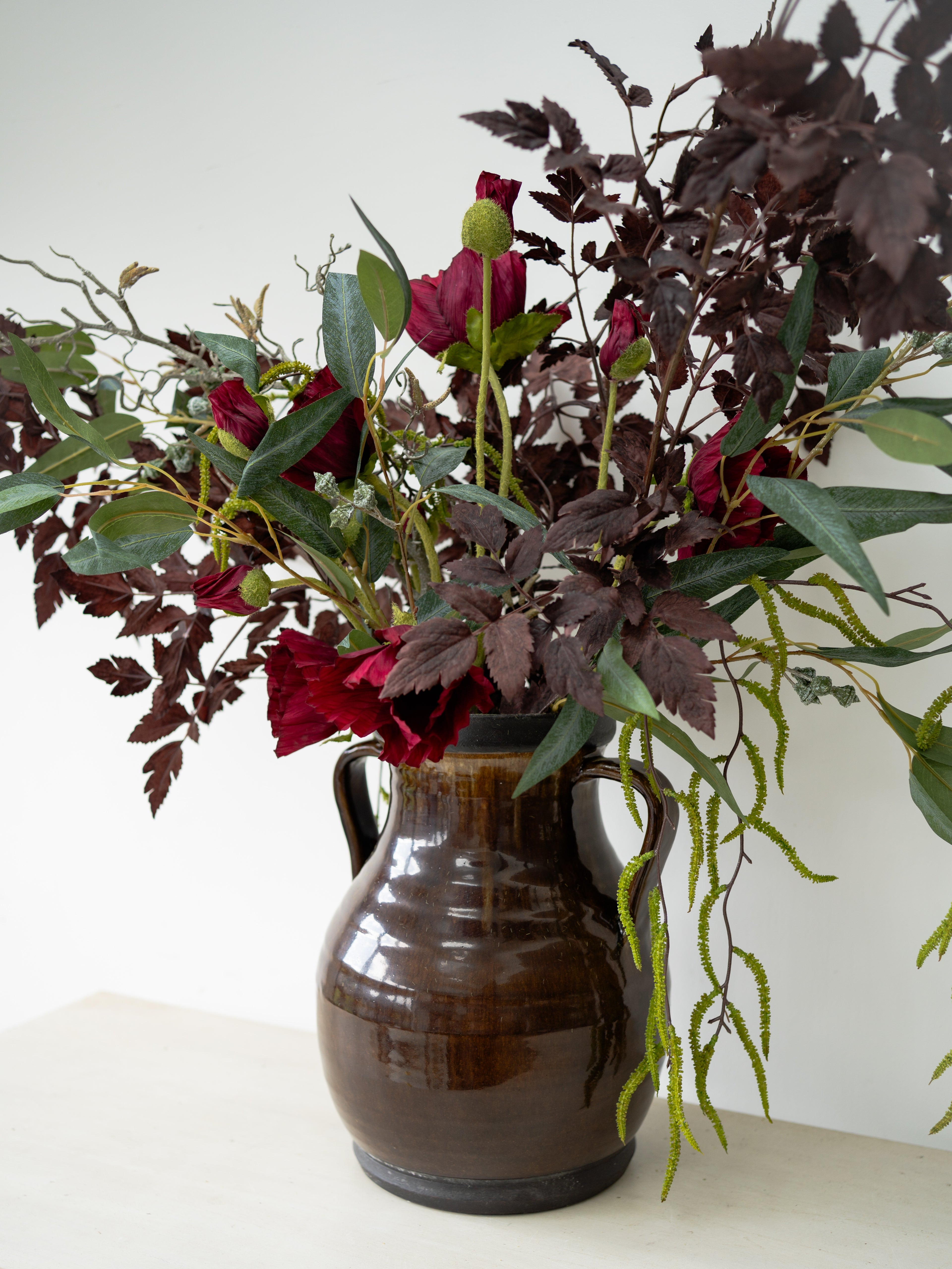 Floral arrangement in a brown vase on a white surface with a white background