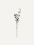 A single dried decorative branch with small brown pine cones, centered on a plain warm off-white background.