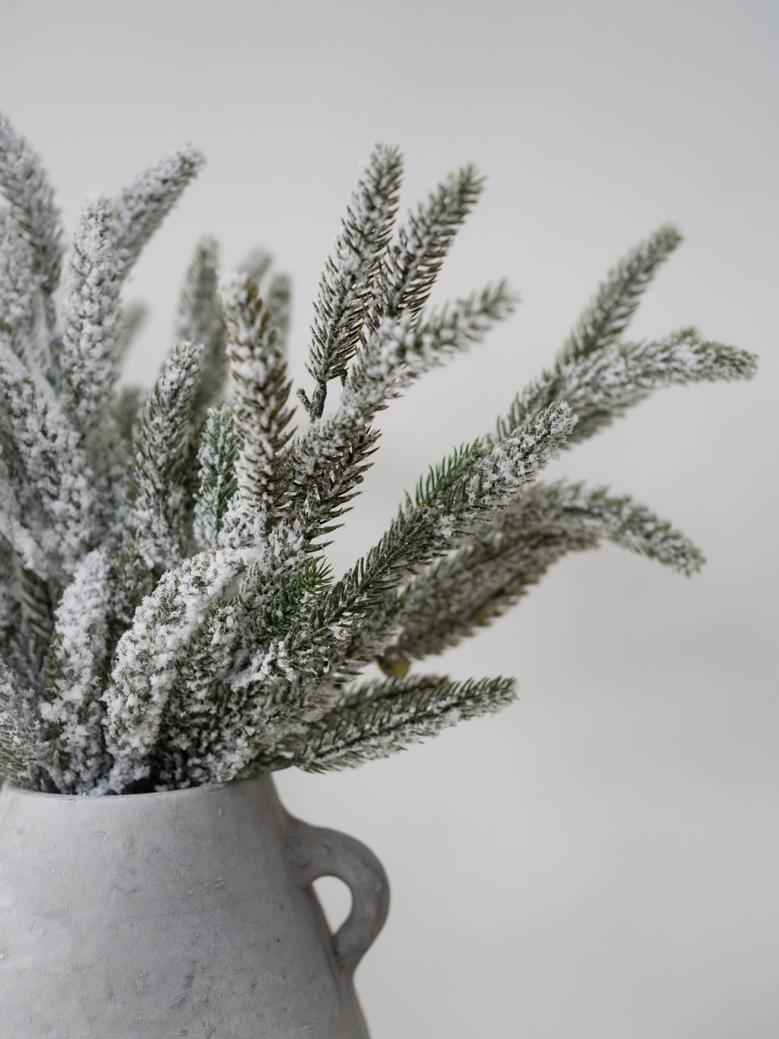 Frosted artificial plants in a gray vase on a light gray background